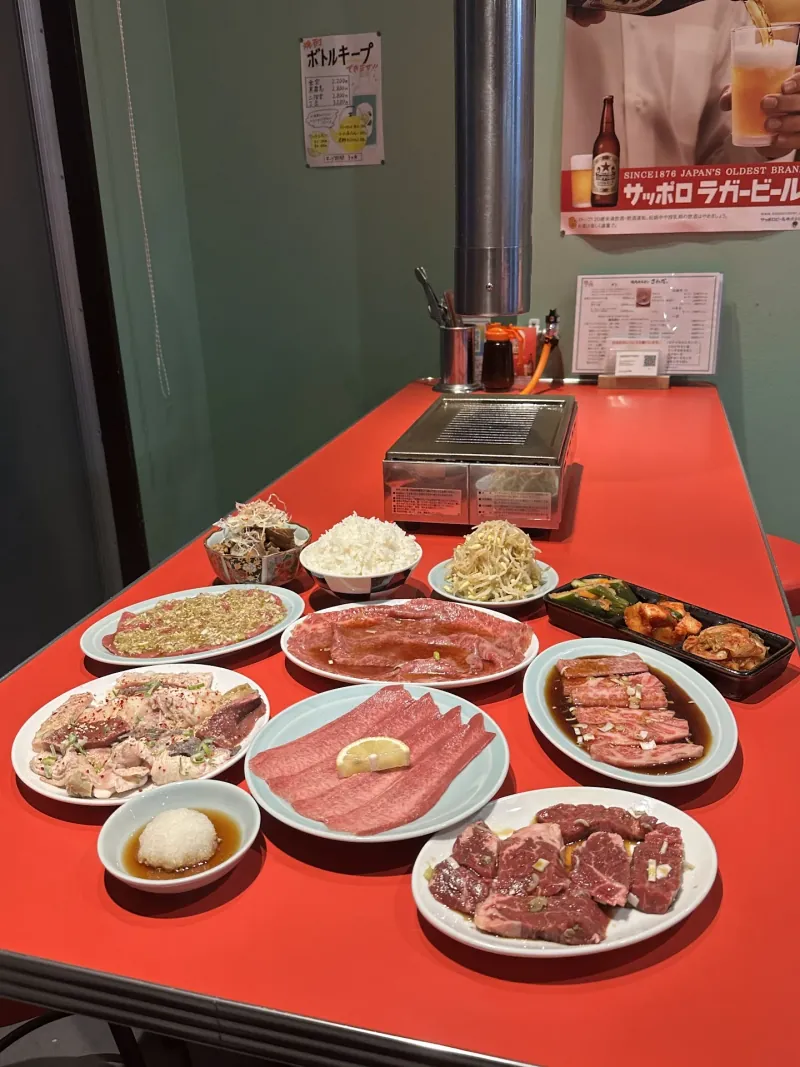 おまかせコースの料理を並べたテーブル。タン塩、カルビ、炙りロース、ハラミ、ミックスホルモン、ナムル、キムチ、ご飯など
